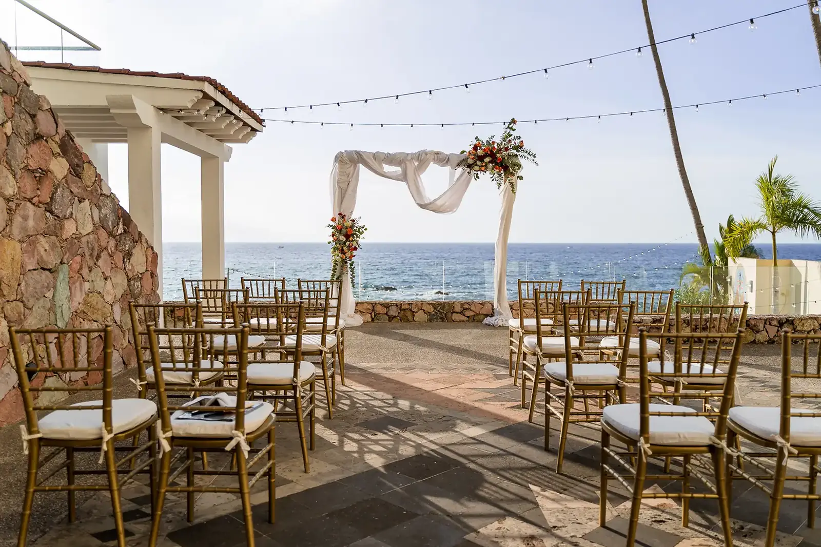 Beachfront wedding ceremony arch with florals and gold chiavari chairs at a Puerto Vallarta wedding venue